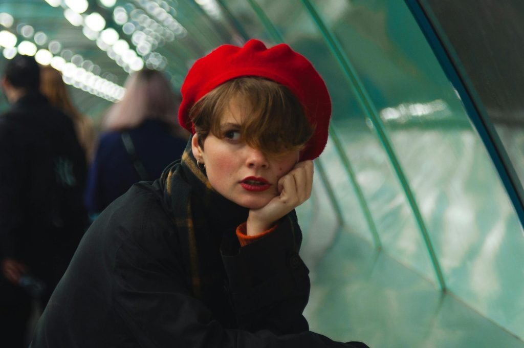 Stylish woman in red beret on a moving walkway in Saint Petersburg tunnel.